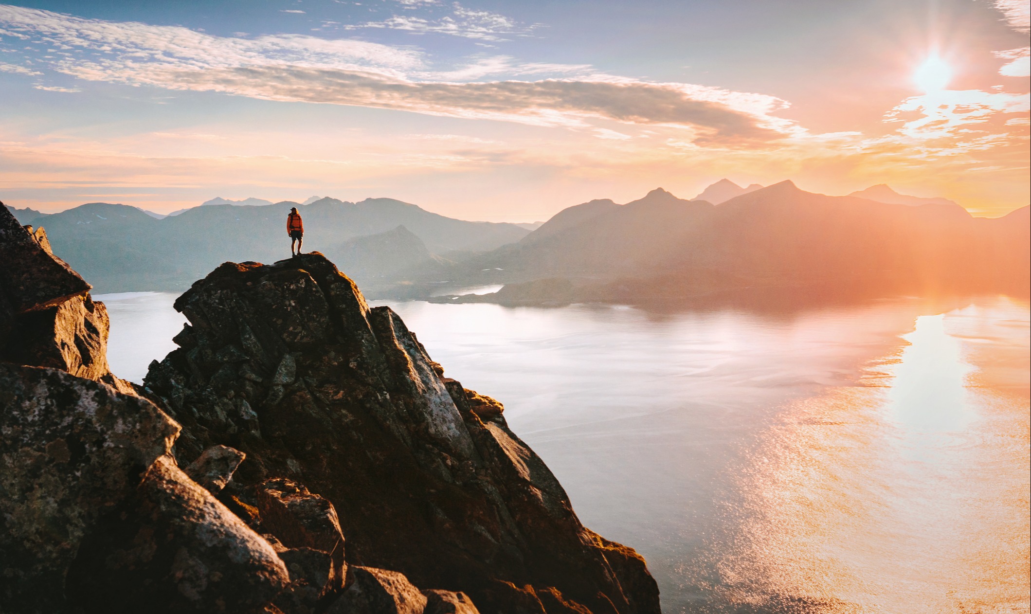 Man climbing mountains enjoying sunset aerial sea view in Lofoten islands