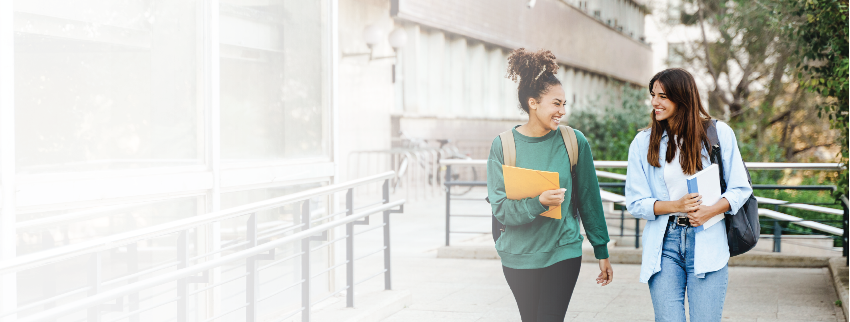 Two happy students walking and talking each other in University campus after classes