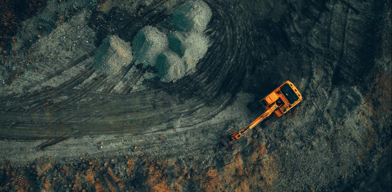 Bright excavator at work on a dark background view from a drone.