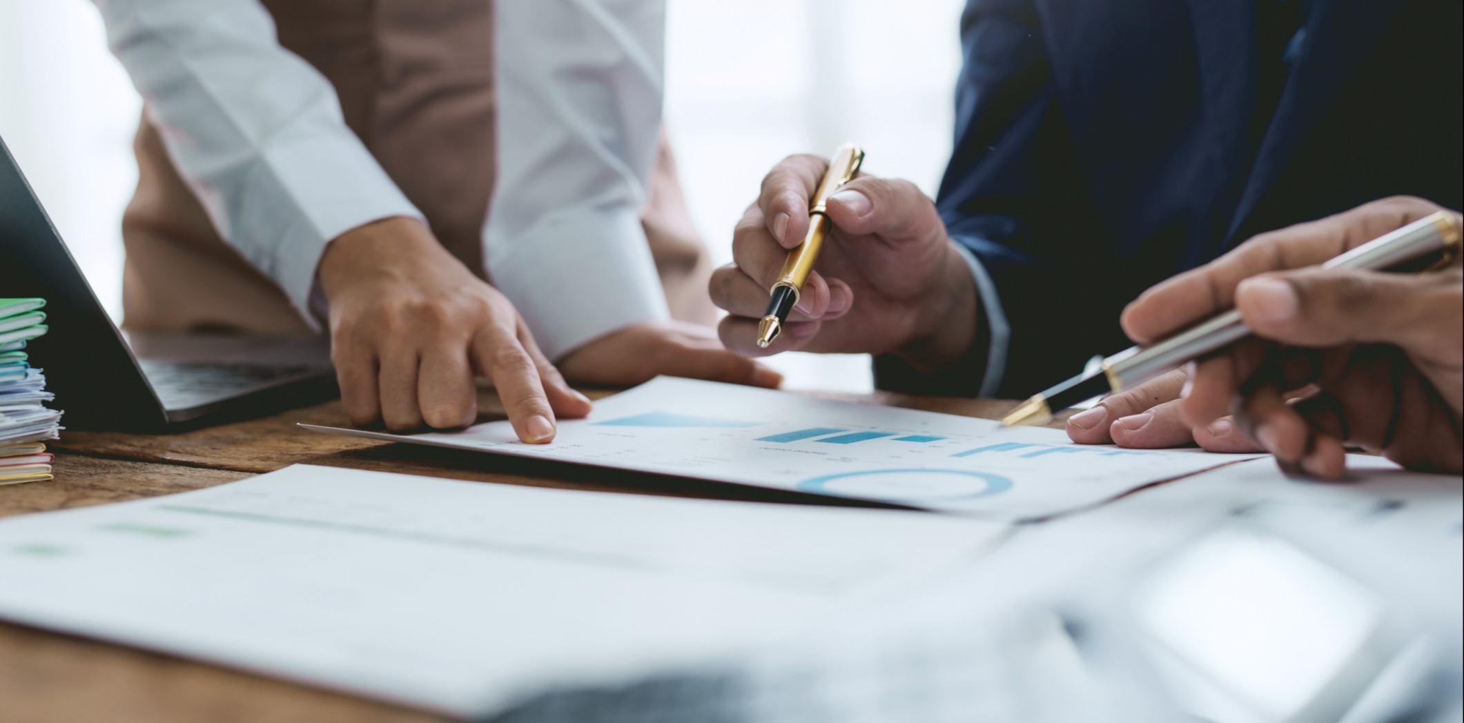 Group of people meeting together pointing to graphs for analysis