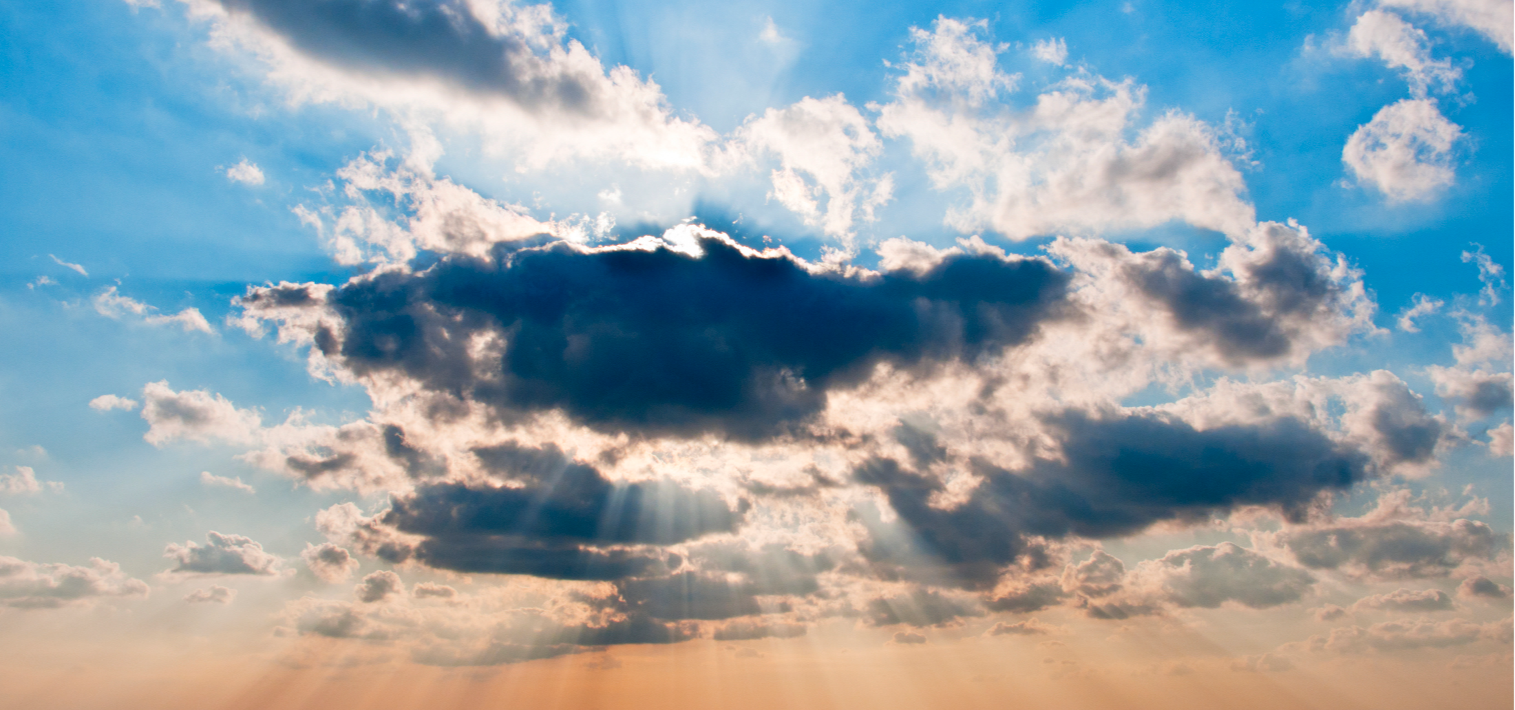 silver lining and sun beams coming out behind a dark cloud in a setting sky